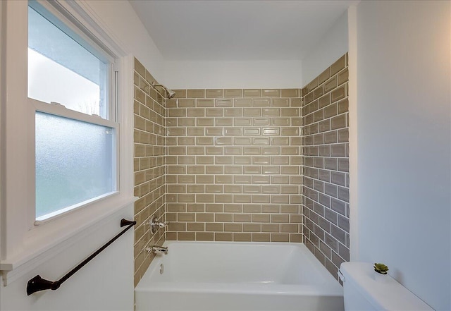 bathroom featuring toilet and tiled shower / bath