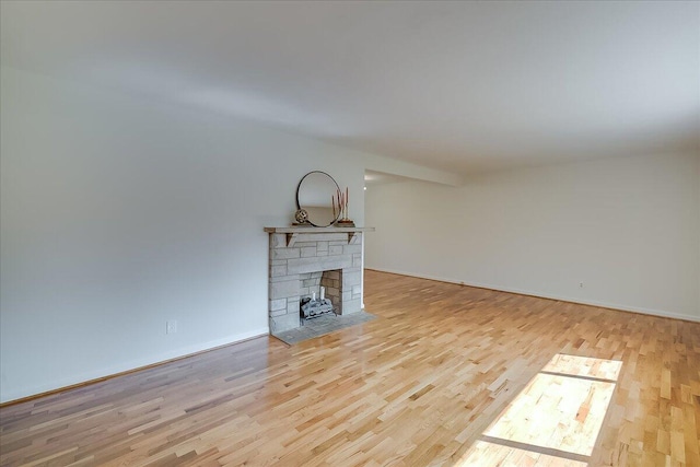 unfurnished living room featuring a stone fireplace and light hardwood / wood-style flooring