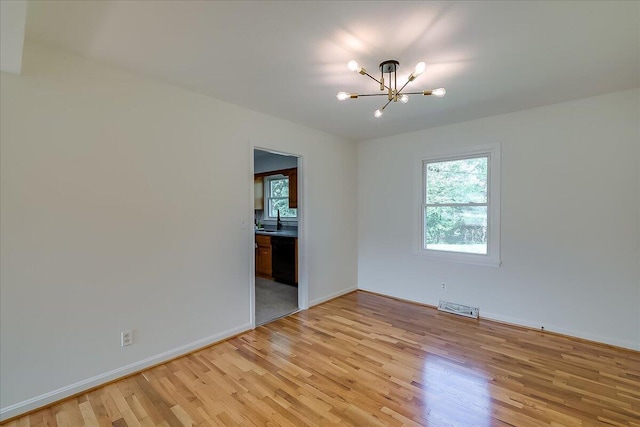 unfurnished room with light hardwood / wood-style flooring, a notable chandelier, and sink