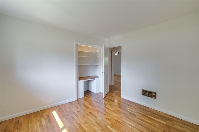 unfurnished bedroom featuring a walk in closet, a closet, and light hardwood / wood-style floors