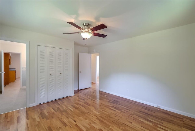 unfurnished bedroom featuring ceiling fan, light wood-type flooring, and a closet