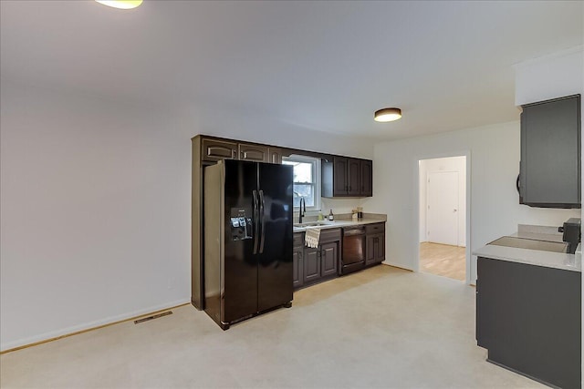 kitchen featuring black appliances, dark brown cabinets, sink, and light carpet