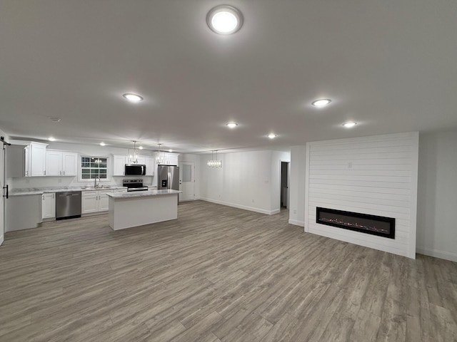 unfurnished living room featuring a chandelier, sink, a fireplace, and light hardwood / wood-style flooring