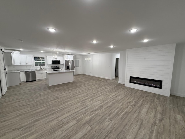 unfurnished living room with a large fireplace, light hardwood / wood-style floors, sink, and a chandelier