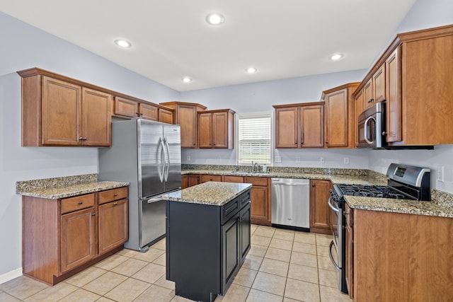 kitchen with light tile patterned floors, sink, stainless steel appliances, light stone countertops, and a kitchen island