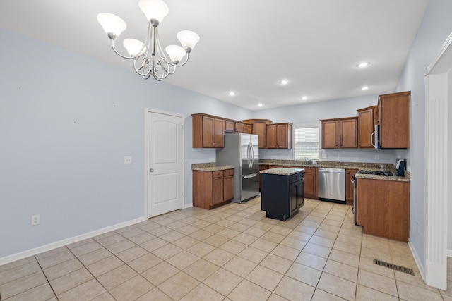 kitchen with visible vents, a kitchen island, appliances with stainless steel finishes, an inviting chandelier, and brown cabinetry