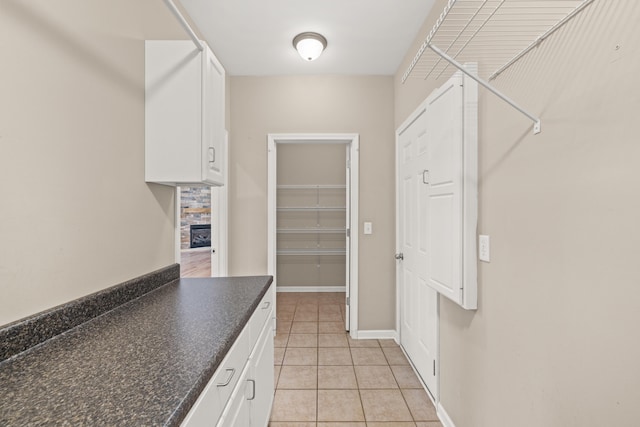 walk in closet with light tile patterned floors and a fireplace