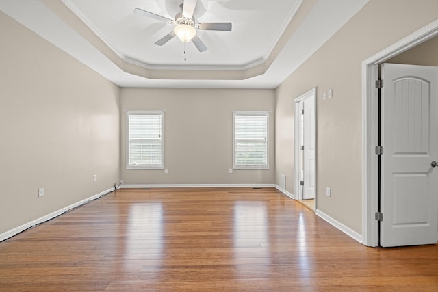 unfurnished room with a raised ceiling, plenty of natural light, and light wood finished floors