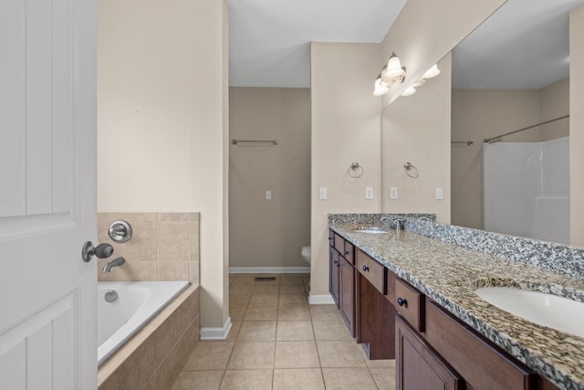 bathroom featuring a relaxing tiled tub, vanity, toilet, and tile patterned flooring