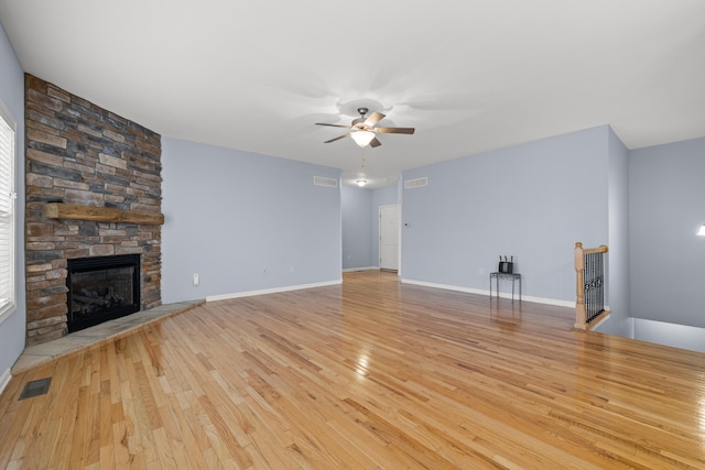 unfurnished living room with ceiling fan, a fireplace, and light hardwood / wood-style flooring