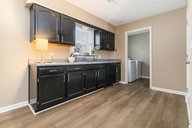 kitchen with hardwood / wood-style flooring, washer and clothes dryer, and sink