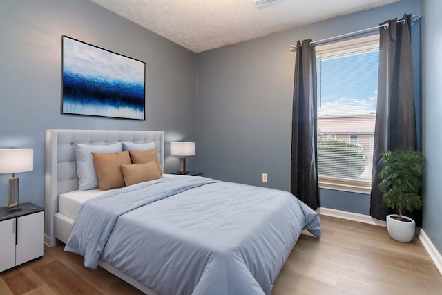 bedroom featuring light hardwood / wood-style floors and a textured ceiling