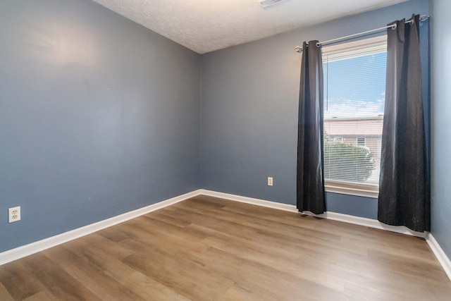 unfurnished room with light hardwood / wood-style flooring and a textured ceiling