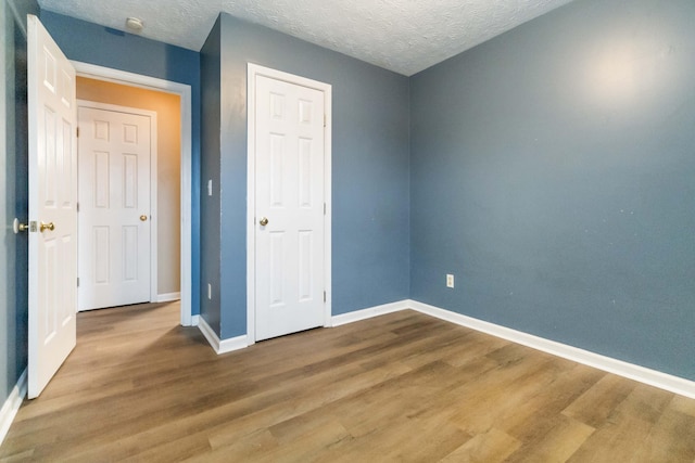 unfurnished bedroom with wood-type flooring and a textured ceiling