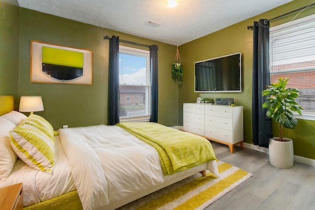 bedroom with light hardwood / wood-style flooring and a textured ceiling