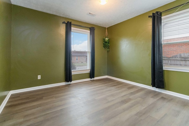 unfurnished room featuring light hardwood / wood-style floors and a textured ceiling