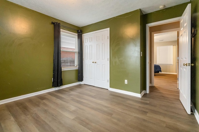 unfurnished bedroom featuring hardwood / wood-style floors, a textured ceiling, and a closet