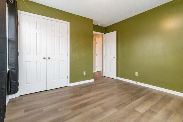 unfurnished bedroom with a closet, a textured ceiling, and hardwood / wood-style flooring