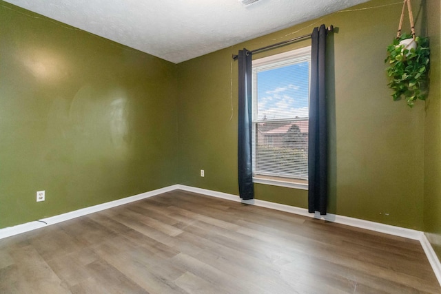 unfurnished room featuring a textured ceiling and light hardwood / wood-style flooring