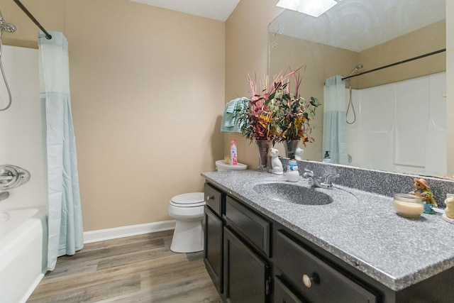 full bathroom featuring a skylight, vanity, shower / tub combo with curtain, hardwood / wood-style flooring, and toilet