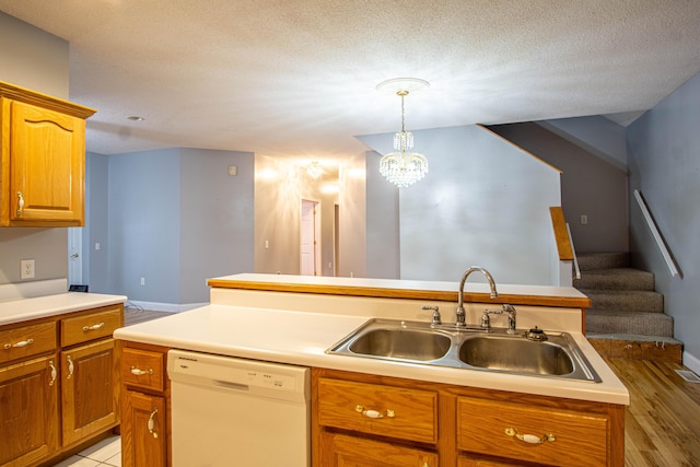 kitchen with white dishwasher, sink, hanging light fixtures, a textured ceiling, and a kitchen island