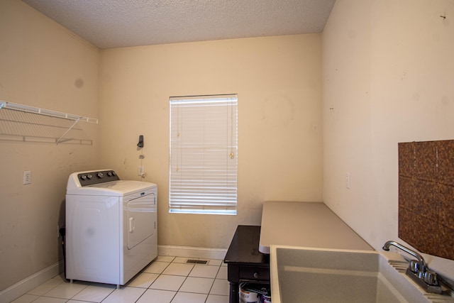 laundry room featuring washer / clothes dryer, sink, light tile patterned floors, and a textured ceiling