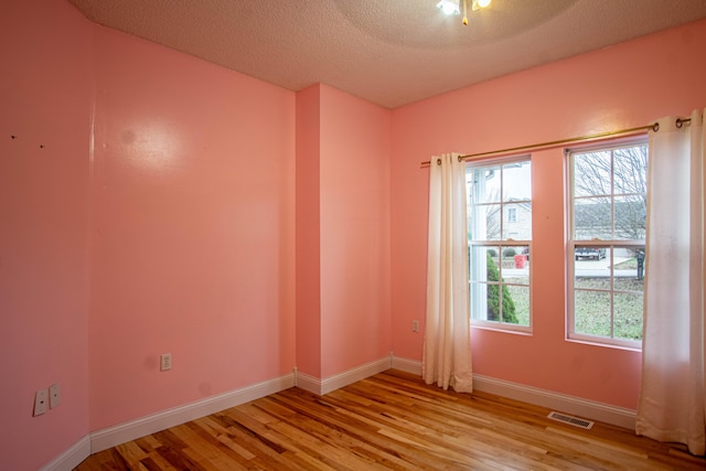 empty room with a textured ceiling and light wood-type flooring