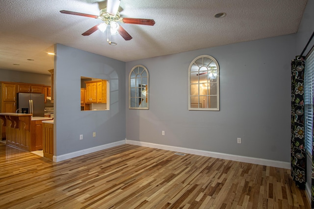 unfurnished room featuring a textured ceiling and light hardwood / wood-style flooring