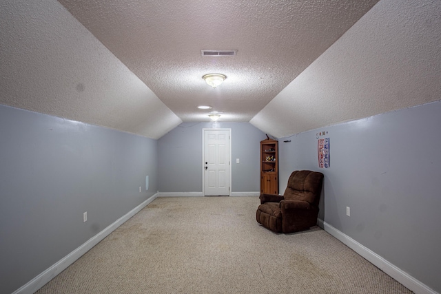 bonus room featuring lofted ceiling, a textured ceiling, and light carpet