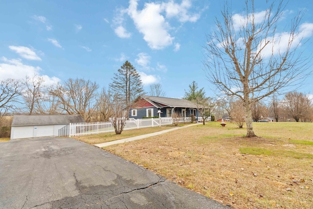 view of front of house featuring an outbuilding, covered porch, a front yard, and a garage