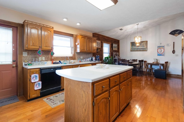 kitchen featuring pendant lighting, dishwasher, a kitchen island, and light hardwood / wood-style flooring