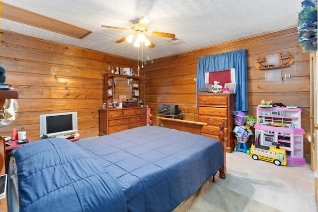 bedroom featuring ceiling fan, carpet floors, a textured ceiling, and wooden walls