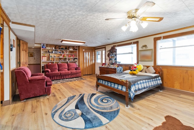 bedroom featuring hardwood / wood-style floors, ceiling fan, wood walls, and ornamental molding