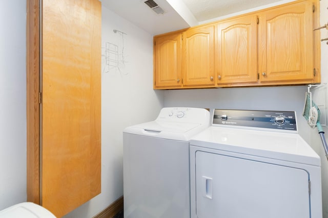 laundry room with washer and clothes dryer, cabinets, and a textured ceiling