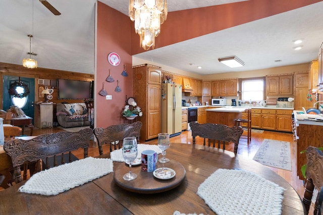 dining room with ceiling fan with notable chandelier and light wood-type flooring