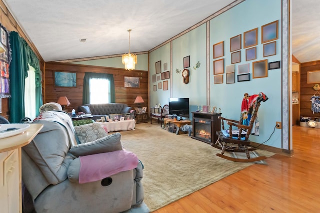 living room featuring an inviting chandelier, hardwood / wood-style flooring, vaulted ceiling, and ornamental molding