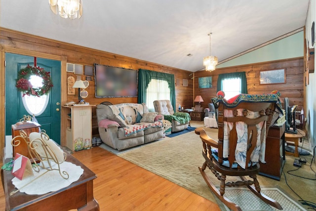 living room with light wood-type flooring, vaulted ceiling, wooden walls, and a notable chandelier