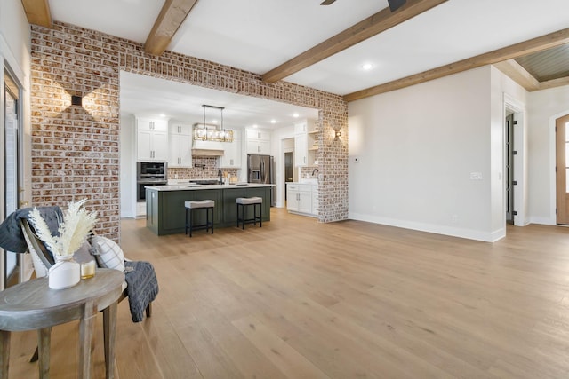 living room featuring ceiling fan, brick wall, beam ceiling, and light hardwood / wood-style flooring