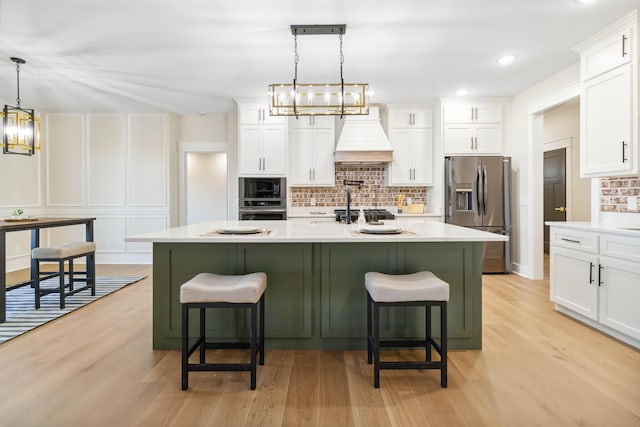 kitchen featuring pendant lighting, white cabinets, appliances with stainless steel finishes, and premium range hood