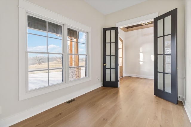 empty room featuring french doors and light wood-type flooring