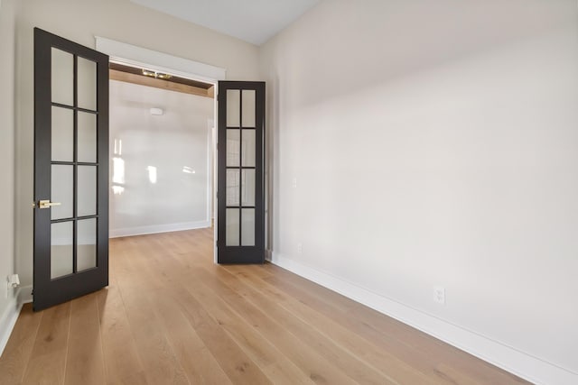 empty room featuring french doors and light wood-type flooring