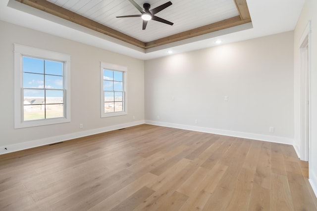 unfurnished room featuring wooden ceiling, a raised ceiling, ceiling fan, and light wood-type flooring