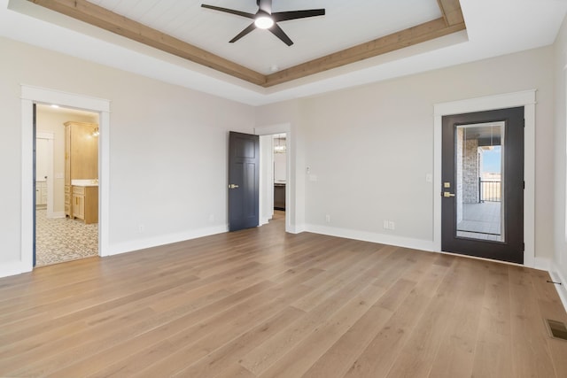 unfurnished living room with a raised ceiling, ceiling fan, and light wood-type flooring