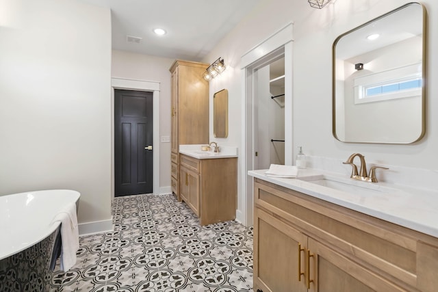 bathroom with a washtub, vanity, and tile patterned floors