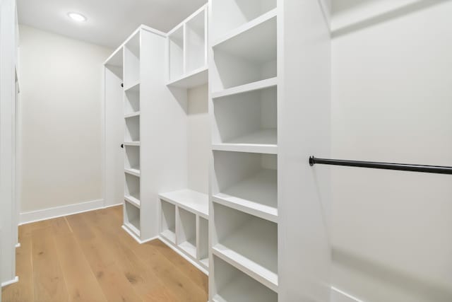 walk in closet with light hardwood / wood-style floors