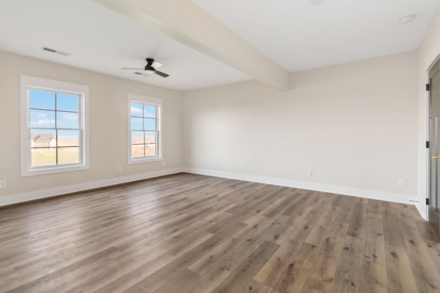 empty room featuring ceiling fan, beam ceiling, and light hardwood / wood-style flooring