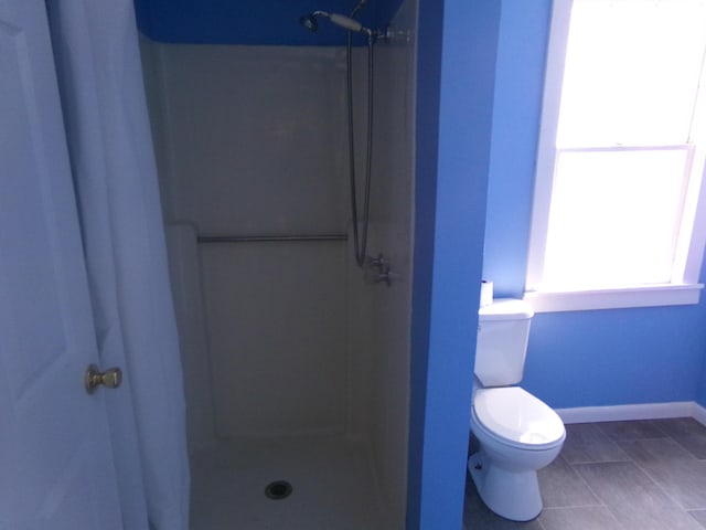 full bath with tile patterned flooring, walk in shower, toilet, and baseboards