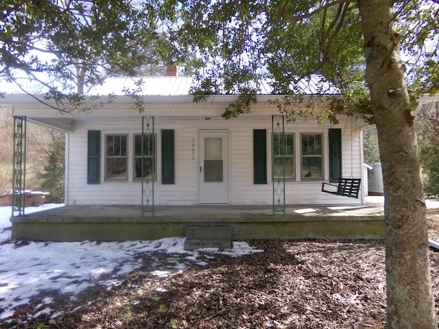 view of front facade featuring covered porch and a chimney