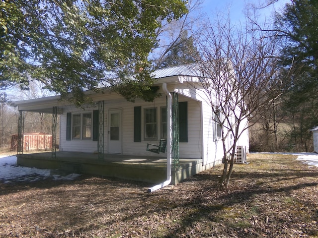 bungalow-style house featuring covered porch, metal roof, and central air condition unit