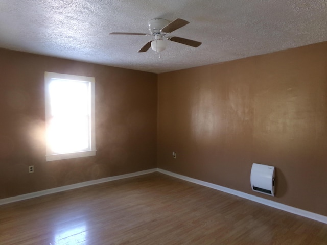 unfurnished room with a textured ceiling, baseboards, and wood finished floors